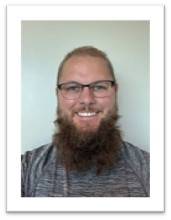 Man with beard, glasses, and a gray shirt.